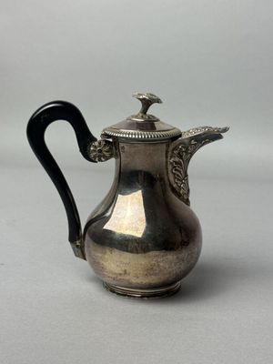 une cafetière ancienne en argent avec une poignée noire sur une surface blanche