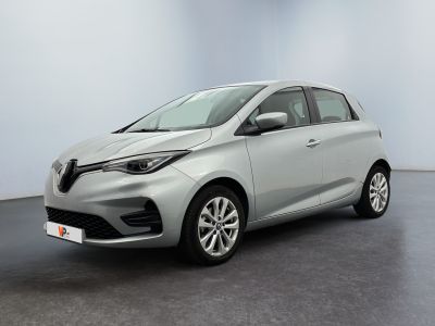 Une voiture argentée est garée dans une pièce aux murs blancs.