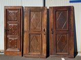 three antique wooden doors sitting in a parking lot next to a building