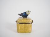 a small blue bird sitting on top of a yellow box