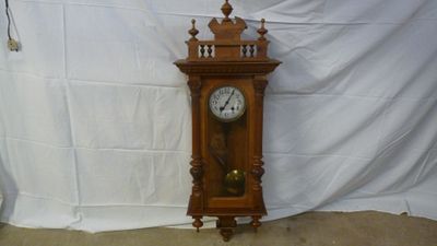 une horloge posée par terre devant un fond blanc