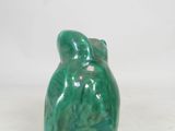 a green ceramic frog figurine sitting on top of a white surface