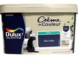 un gros plan sur un pot de peinture, avec un chat assis par terre