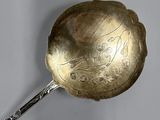 a silver spoon with a handle that has a design on it