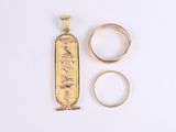 two gold rings and an egyptian hierole on a white surface