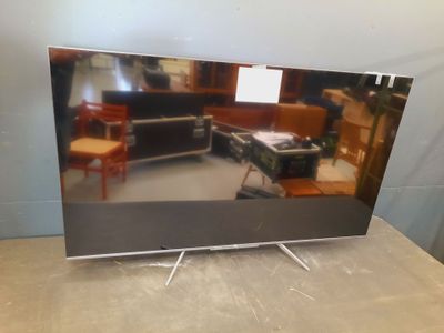 television sitting on top of a table in a room with a piano in the background