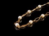 collier de perles et d'or sur fond noir
