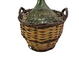 une bouteille en verre vert posée dans un panier en osier