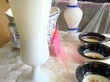 a white vase sitting on a table next to other bowls
