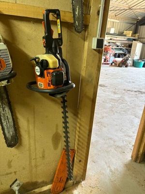 une photo représentant une tronçonneuse et une autre tronçonneuse accrochée au mur