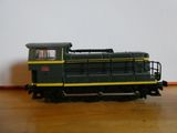 une locomotive verte et jaune posée sur un plancher en bois