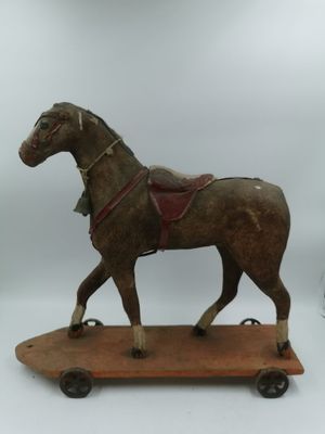 un cheval en bois muni d'une selle, posé sur un skateboard