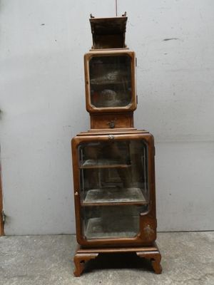 a tall wooden cabinet with a glass door on top of it