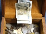 a wooden box full of coins and money sitting on the floor