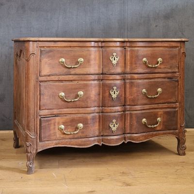 an antique chest of drawers on a wooden floor against a gray wall