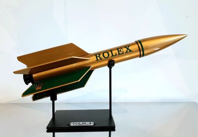 une maquette de fusée dorée et verte posée sur un socle noir