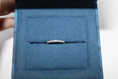 someone is holding a ring in a blue box with a diamond band