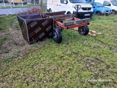un chariot sur lequel se trouve une caisse, dans l'herbe