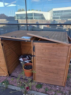 a wooden shed with a door open on the side of the street