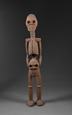 une sculpture représentant un squelette tenant une tête humaine