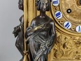 a gold clock with blue roman numerals on it