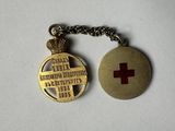 a close up of a keychain with a red cross on it