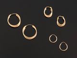 five pairs of gold hoop earrings on a black surface