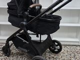 a black stroller with a baby in it sitting on a tiled floor