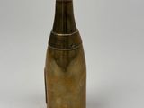a small brass bottle with a handle on a white surface