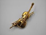 a close up of a gold violin pin on a white surface