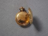 a small gold pocket watch on a blue cloth