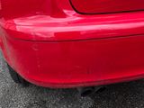 l'arrière d'une voiture rouge dont le pare-chocs porte une plaque d'immatriculation