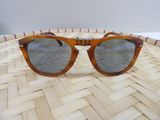 sunglasses on a woven basket on a table with a white wall in the background