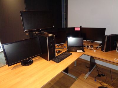un bureau sur lequel se trouvent trois écrans d'ordinateur et un clavier