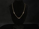 a gold necklace on a black mannequin with a black background