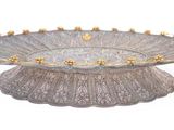 a silver plate with gold decorations on it on a white surface