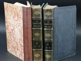three books are stacked on top of each other on a black surface
