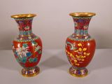 une paire de vases rouges ornés de motifs floraux, posés sur une table