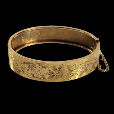 gros plan d'un bracelet en or sur fond noir