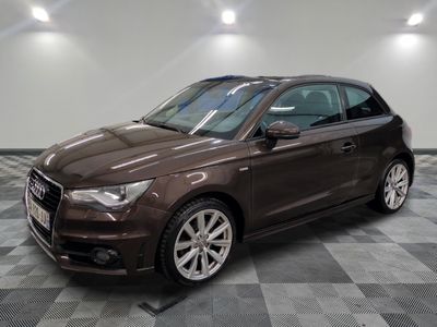 L'Audi marron est garée dans une grande pièce au sol carrelé.