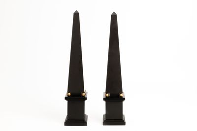 paire d'obélisques en fer noir rehaussés de touches dorées, posés sur des socles