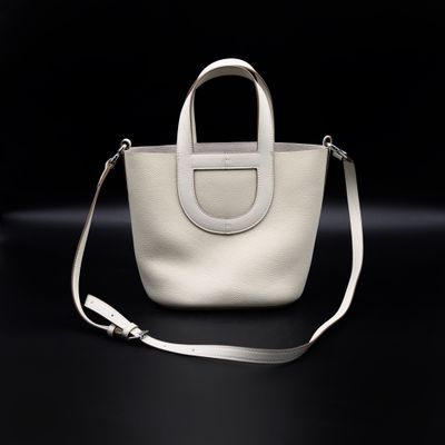 a white purse with a long strap on a black background
