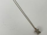 a silver necklace with a bird on it sitting on top of a white surface