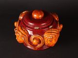 a red jar with a wooden lid on a black surface