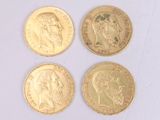quatre types différents de pièces d'or reposant sur une surface blanche