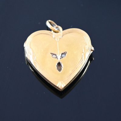 a gold heart shaped locke with a bird on it
