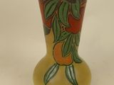 a yellow vase with oranges and leaves painted on it