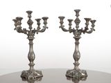 une paire de bougeoirs plaqués argent posés sur une table ronde en verre