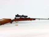 a rifle on a white background with a red dot on the side of the rifle