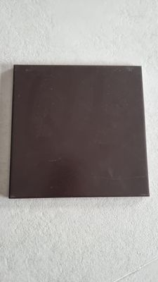 un gros plan sur un carreau carré noir posé sur une surface blanche